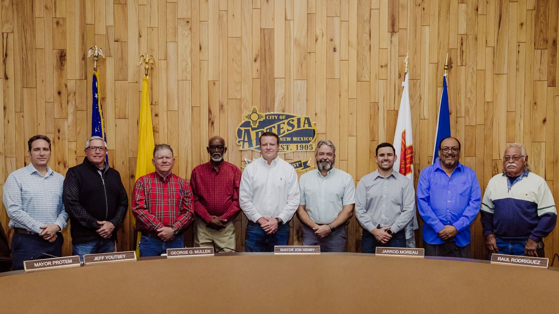 Photograph of each council member standing in Council Chambers with legacy logo on back wall